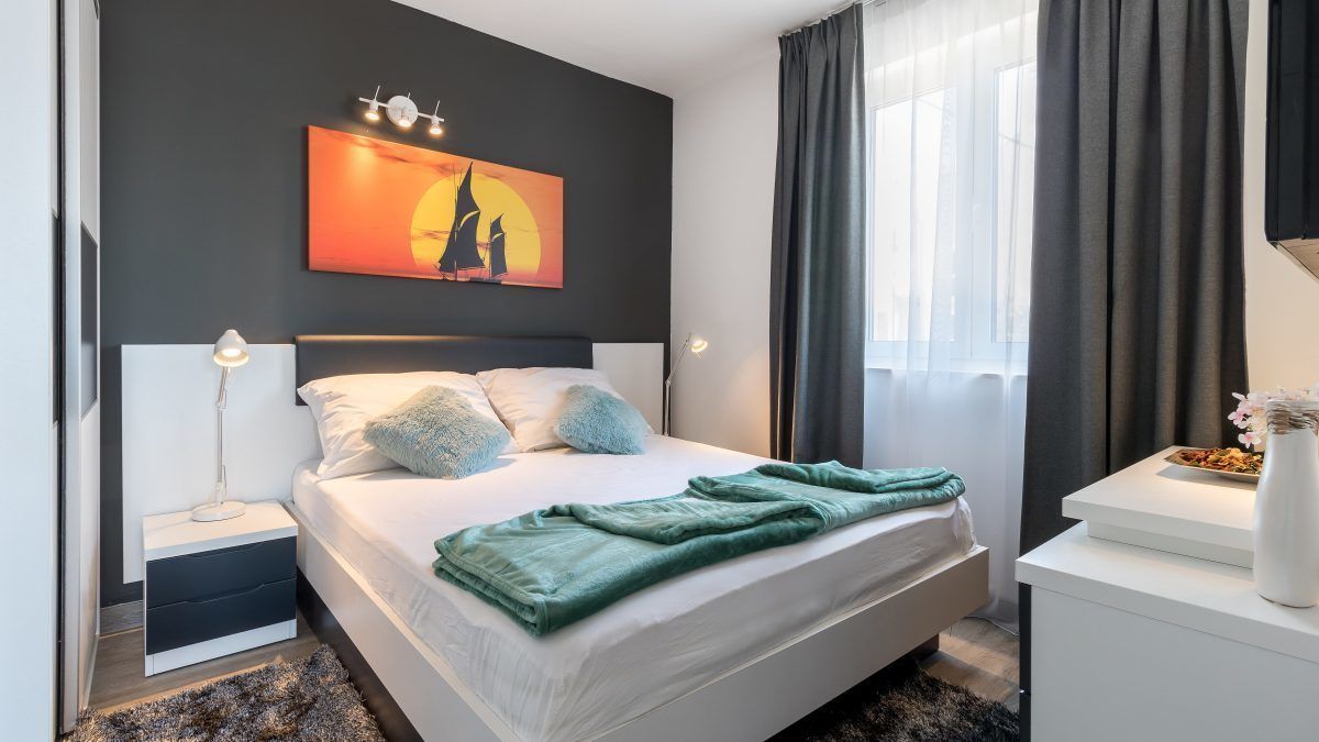 Une chambre à coucher moderne avec un lit, des lampes de chevet, une table de chevet, un tableau et une fenêtre avec des rideaux.