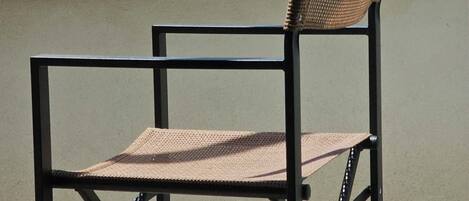 A chair on a balcony overlooking a coastal view with a clear sky and distant land.