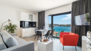 Une chambre d’hôtel moderne dotée d’une cuisine, d’un coin repas et d’un grand balcon offrant une vue sur la mer.