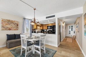 A modern kitchen with white cabinets, a black refrigerator, and a dining area with a white table and chairs.