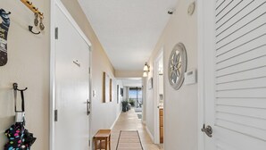 Un couloir avec un banc, un tapis et une porte sur laquelle est apposée une pancarte.