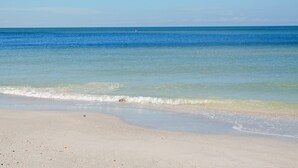Une plage avec une eau d’un bleu limpide et un rivage sablonneux.