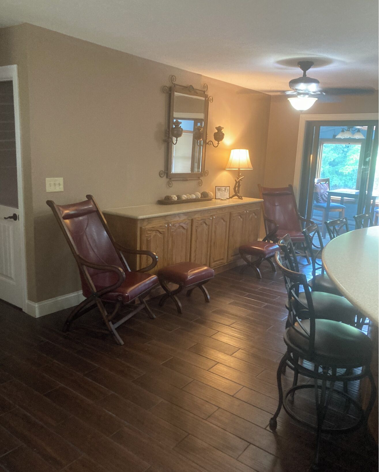 A dining area with a wooden table and chairs, a mirror, and a ceiling fan.