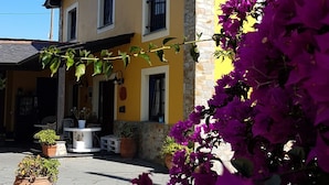 Un edificio amarillo con fachada de piedra, un balcón y macetas con plantas.