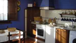 Una cocina con una mesa de madera, estufa, lavavajillas y fregadero.