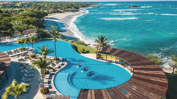 Un resort con una piscina grande, playa y vistas al océano.