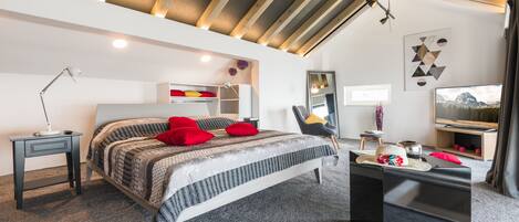 A modern bedroom with a bed, bedside table, and a black ottoman.
