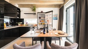 Cocina moderna con comedor, que incluye una mesa de madera con copas de vino, una botella de vino y un sombrero.