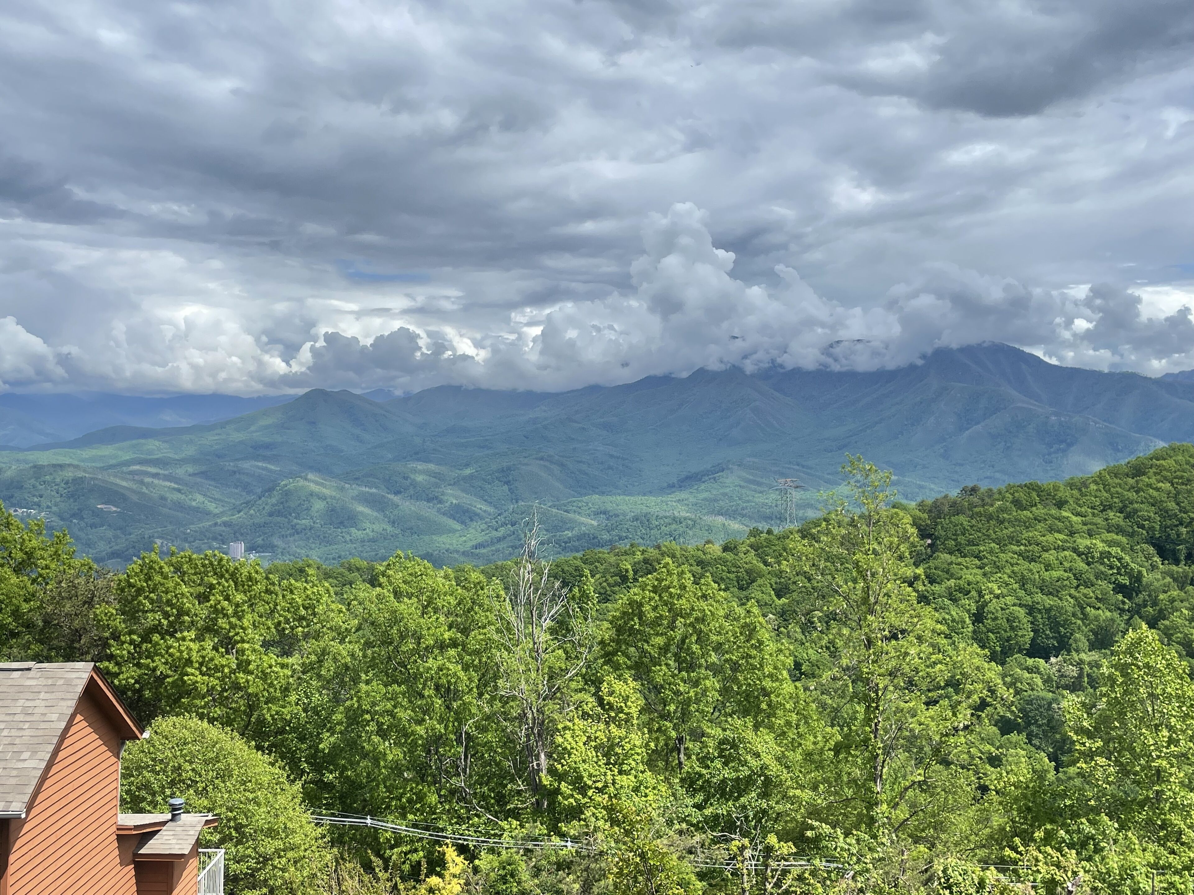 A residential area with a house in the foreground and a mountainous landscape in the background.