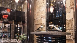 Un vestíbulo con candelabros, una pared de piedra y un mostrador de recepción con adornos.