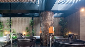 Un área de spa con dos jacuzzis, una terraza de madera, plantas de bambú y un muro de bambú.