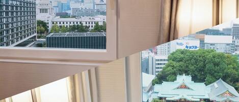 A hotel room with a view of a cityscape and a traditional building.