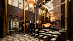 Un vestíbulo lujoso con suelo de mármol, un gran candelabro y una zona de bar moderna.