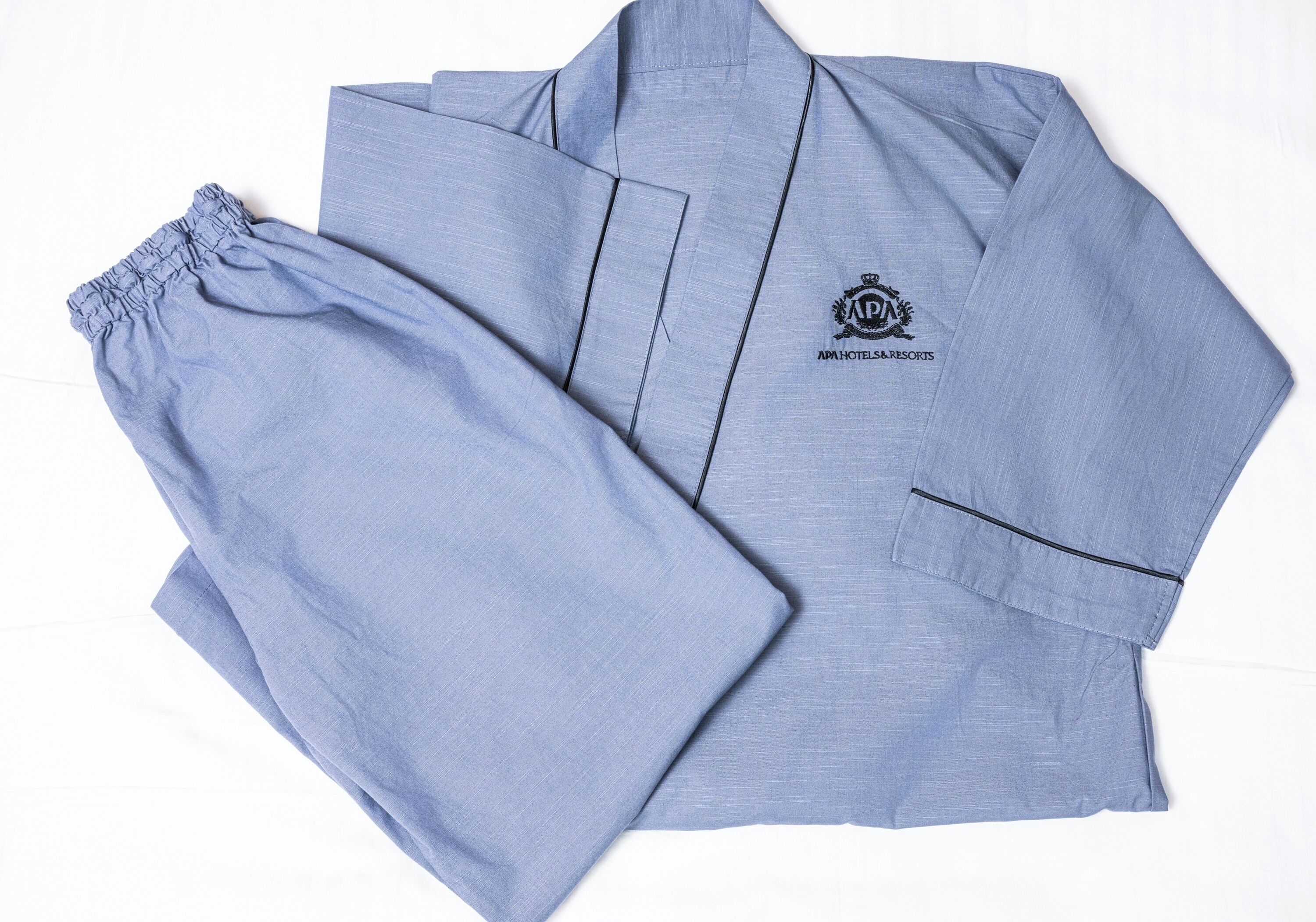 A light blue pajama set with a logo and text indicating it is from APA Hotels & Resorts.