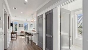 A modern kitchen with a central island, a dining area with a white sofa, and a hallway leading to a door.