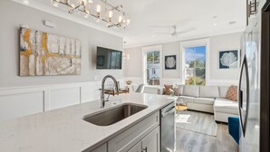 A modern kitchen with a large island, stainless steel appliances, and artwork on the walls.
