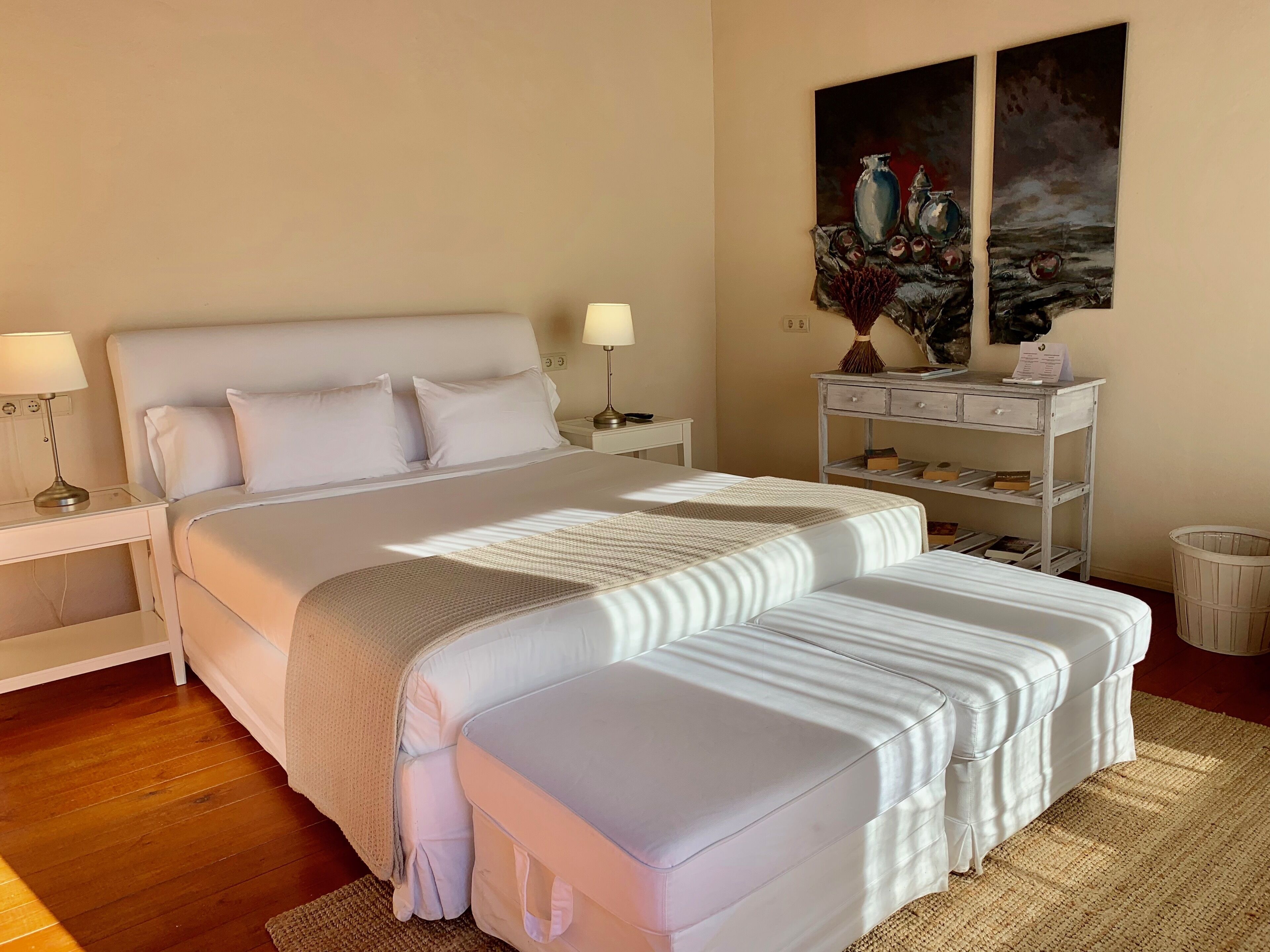 Un dormitorio ordenado con una cama grande, mesitas de noche y un estante en la pared con adornos.