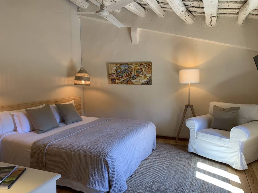 Ein Schlafzimmer mit Bett, Nachttisch, Lampe und einem Sessel.