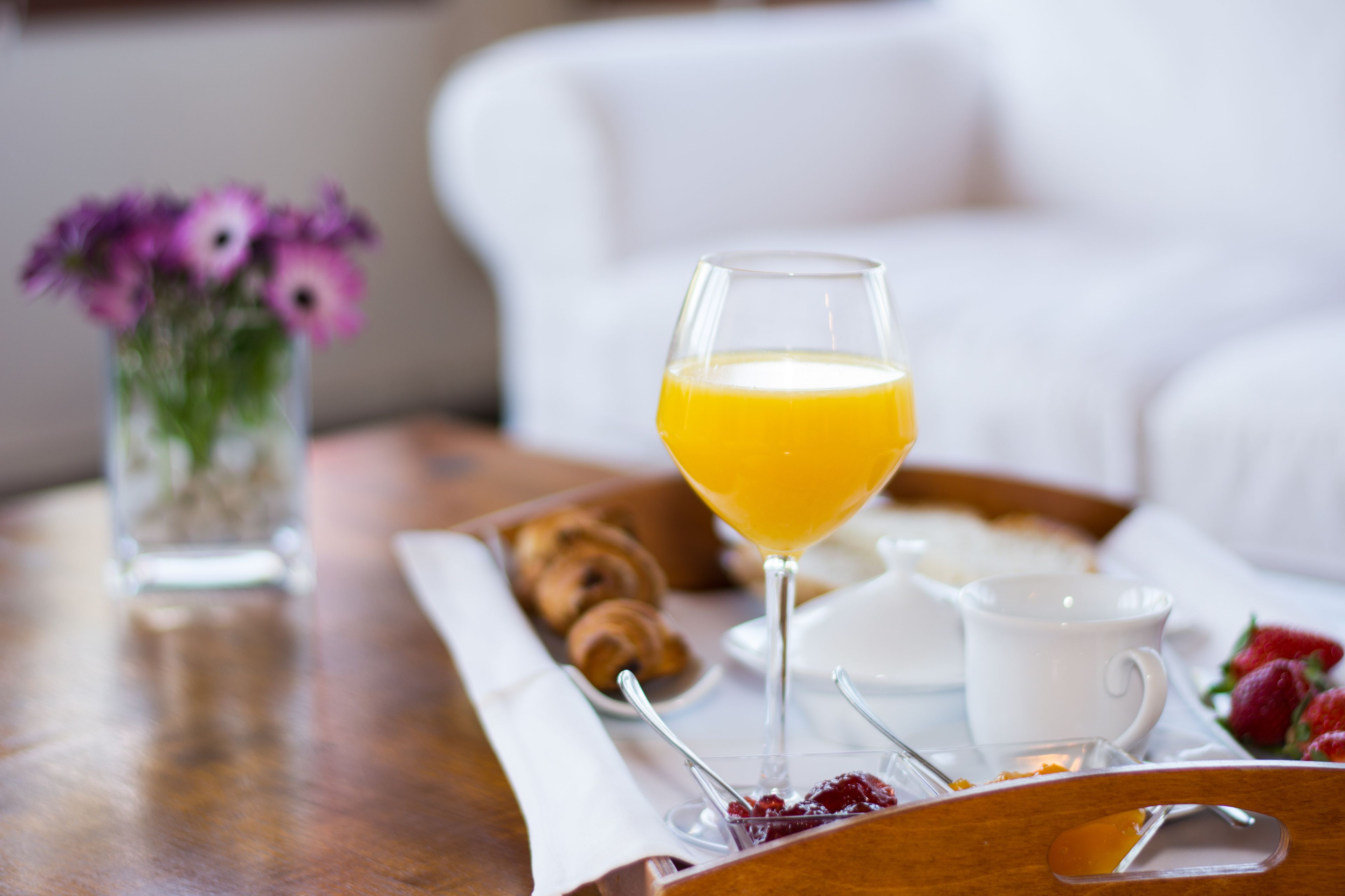 Bandeja de café da manhã com croissants, copo de suco de laranja, xícara de café e morangos.