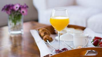 Bandeja de café da manhã com croissants, copo de suco de laranja, xícara de café e morangos.