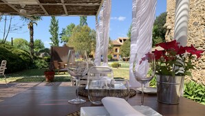 An outdoor dining area with a table set for two, including wine glasses, plates, and a napkin. - Hotel Masia la Palma (Cabanelles)