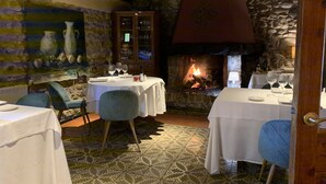 A restaurant with stone walls, a fireplace, and tables set for dining. - Hotel Masia la Palma (Cabanelles)