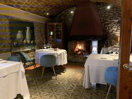 Un restaurante con paredes de piedra, chimenea y mesas dispuestas para comer.
