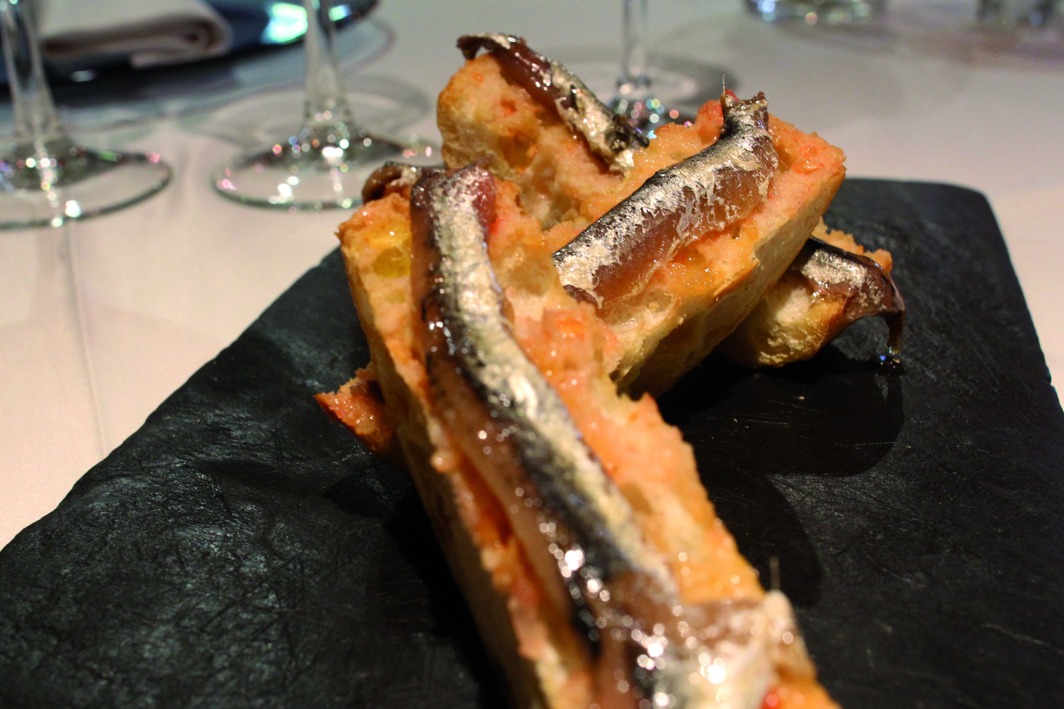 Un plato de pescado a la parrilla sobre una losa de pizarra negra.