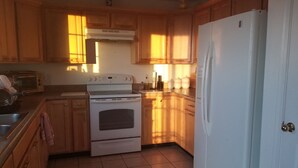 A kitchen with wooden cabinets, a white stove, a microwave, and a refrigerator. - Tranquil Retreat with Gorgeous near 360-degree Mountain Views! (Rio Rico)