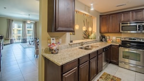 A modern kitchen with granite countertops, stainless steel appliances, and dark wood cabinets.