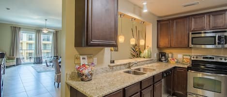 Una cocina moderna con encimeras de granito, electrodomésticos de acero inoxidable y armarios de madera oscura.