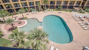 A pool area with lounge chairs and palm trees.