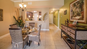 A dining area with wicker chairs, a round table, and a chandelier.