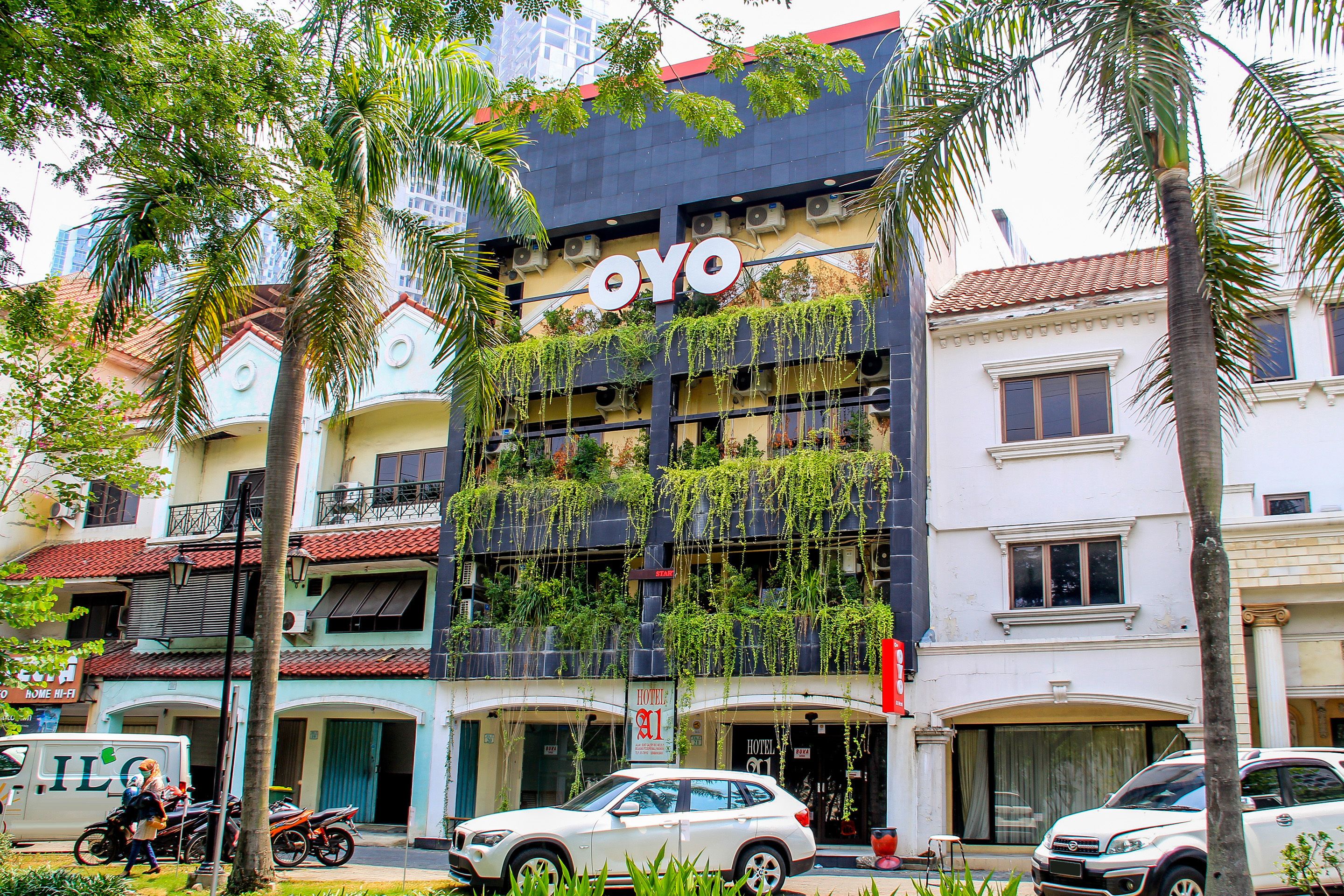 A hotel with a sign reading "OYO" and a balcony with plants.