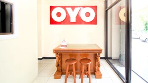 Interior de restaurante com balcão e bancos de madeira, um grande letreiro 'OYO' na parede e uma janela com vista para a rua.