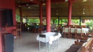 An outdoor covered dining area with tables and chairs, ceiling fans, and a television screen. - Big Foot Safari Lodge (Wli)