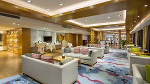 A spacious hotel lobby with multiple seating areas, a reception desk, and a large television screen. - Zhangjiajie Huatian Hotel (Zhangjiajie)
