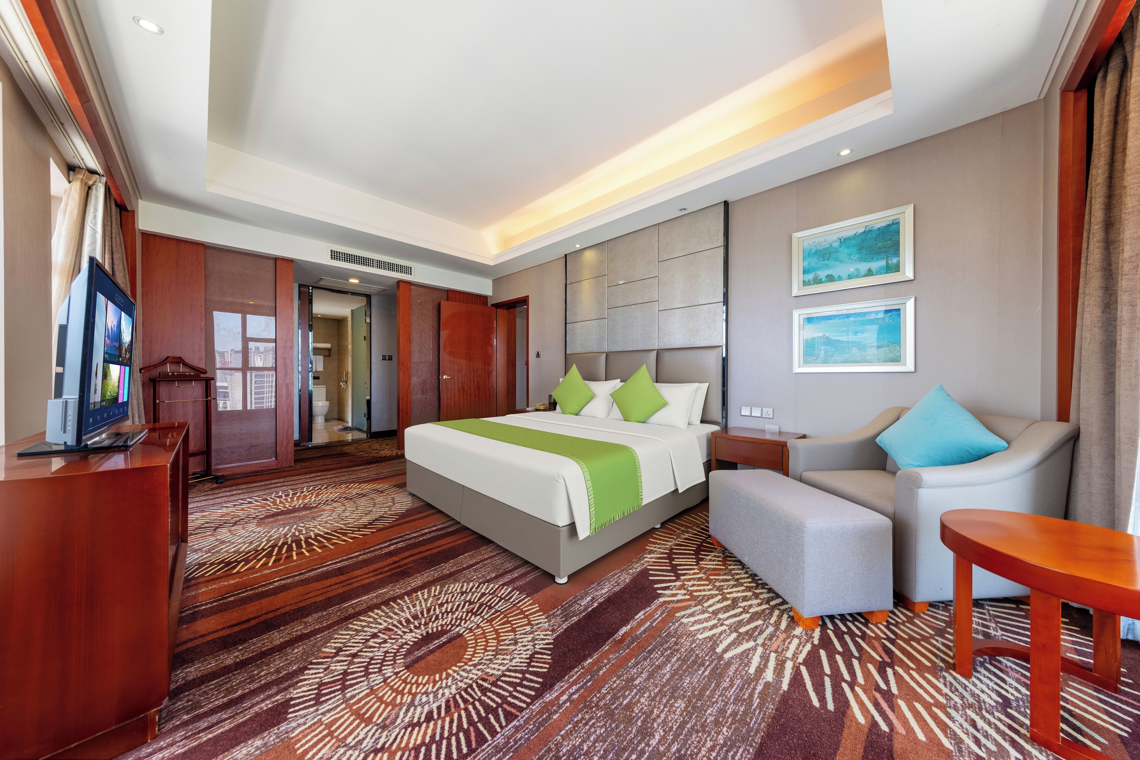 Een hotelkamer met een bed, een bank, een televisie en een bureau.