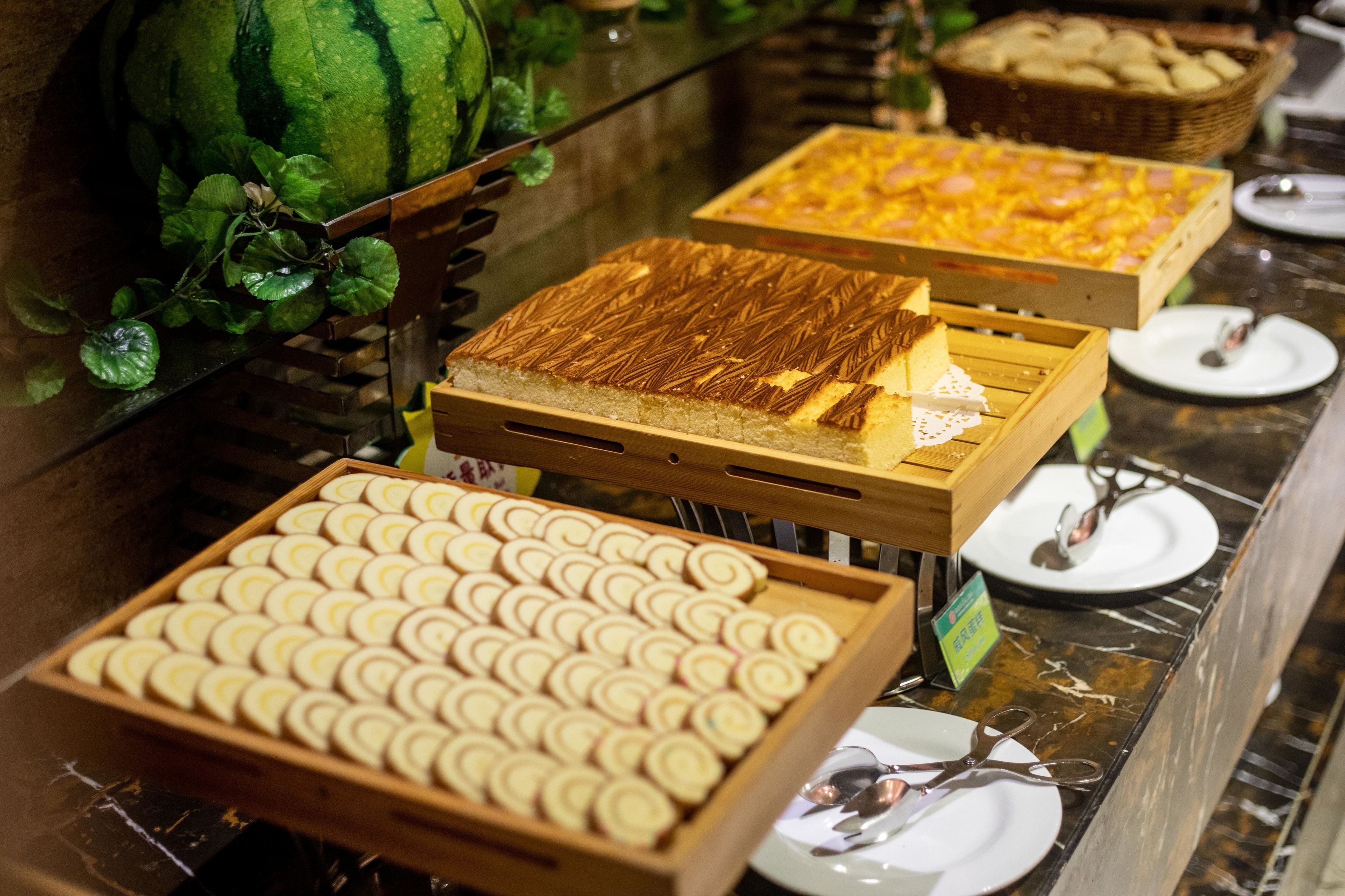 Un bufé con diversas opciones de comida, incluyendo pasteles, una sandía y una pizza.