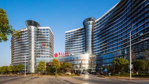 A modern building with curved glass facades and multiple floors. - Zhangjiajie Huatian Hotel (Zhangjiajie)