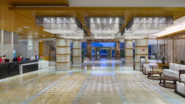 A spacious lobby with a marble floor, a reception desk, and a seating area with sofas and a coffee table. - Zhangjiajie Huatian Hotel (Zhangjiajie)