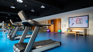 A gym with treadmills, a wall-mounted screen displaying text, and a bench. - Zhangjiajie Huatian Hotel (Zhangjiajie)