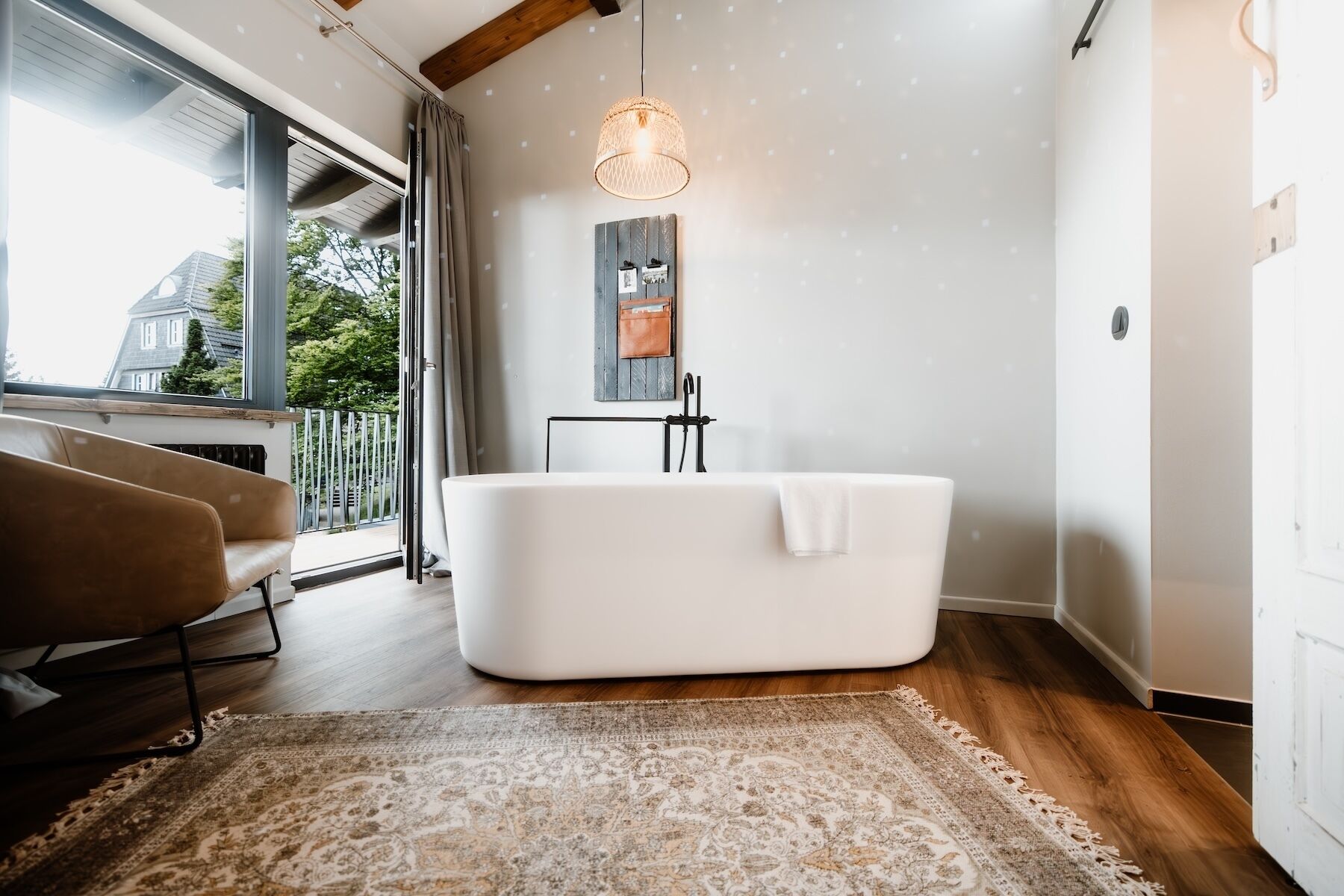 Une salle de bain moderne avec une baignoire sur pieds, une grande fenêtre et un luminaire suspendu.