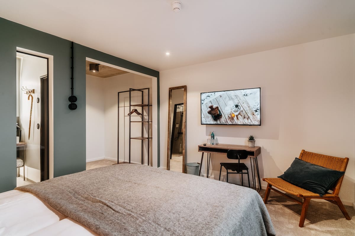 A bedroom with a bed, a desk, a chair, and a wall-mounted TV.