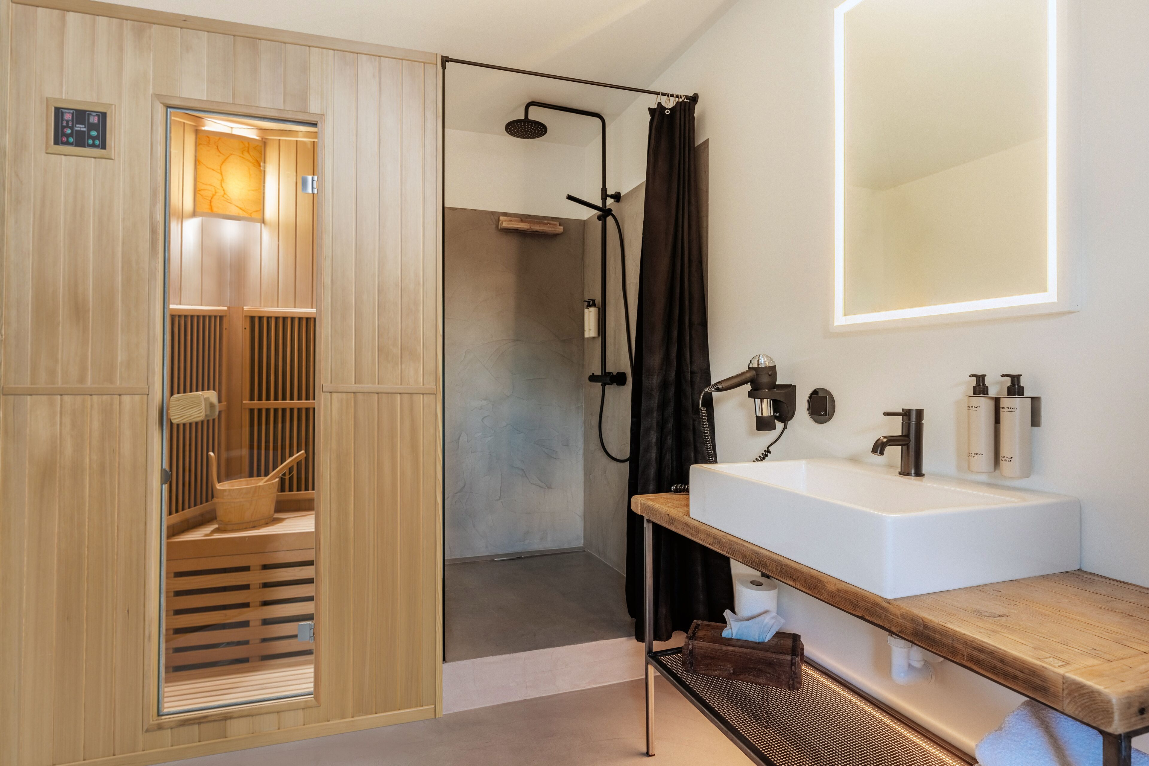 A modern bathroom with a wooden sauna, a large mirror, and a white sink.