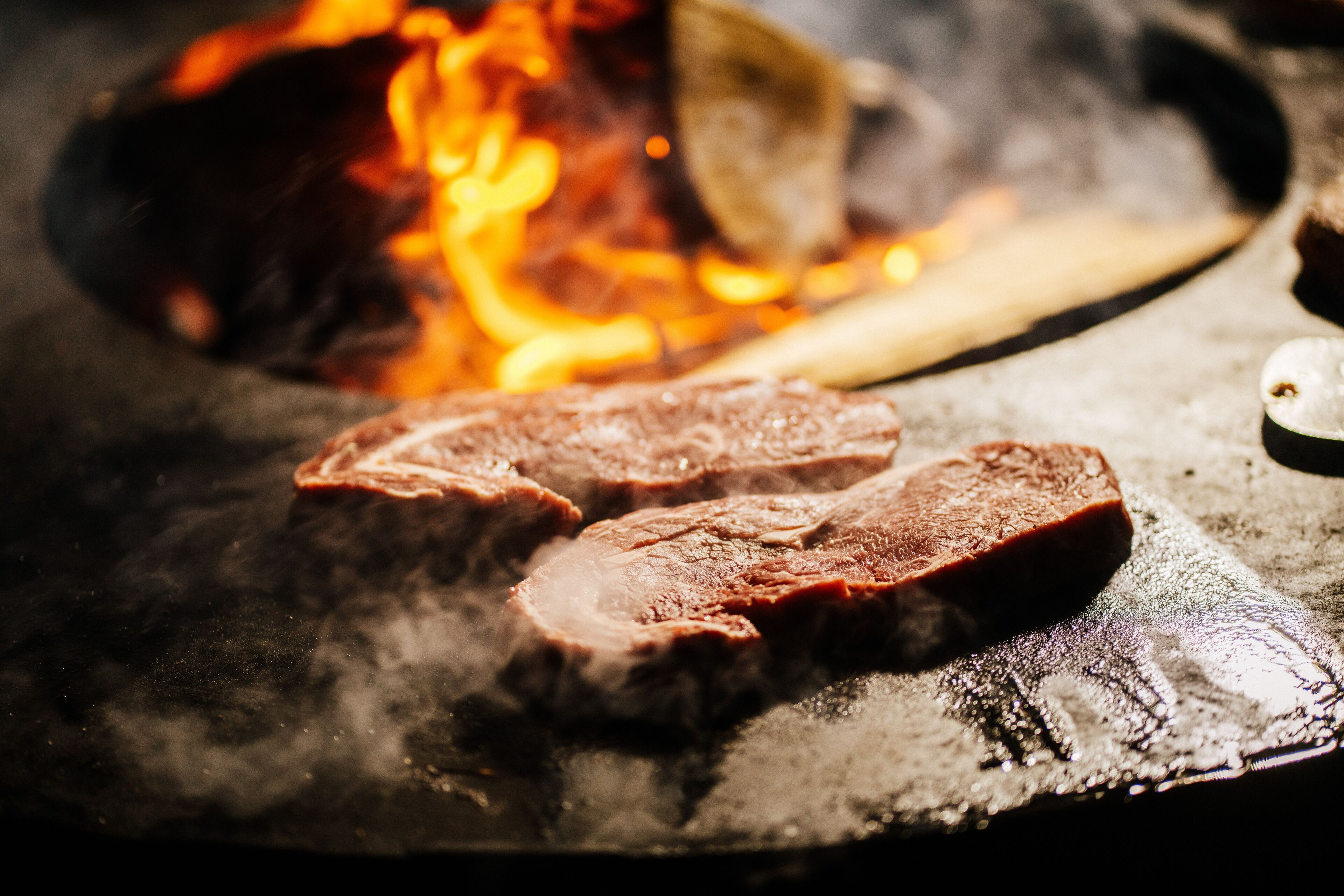 Un primo piano della carne che viene grigliata su una fiamma viva.