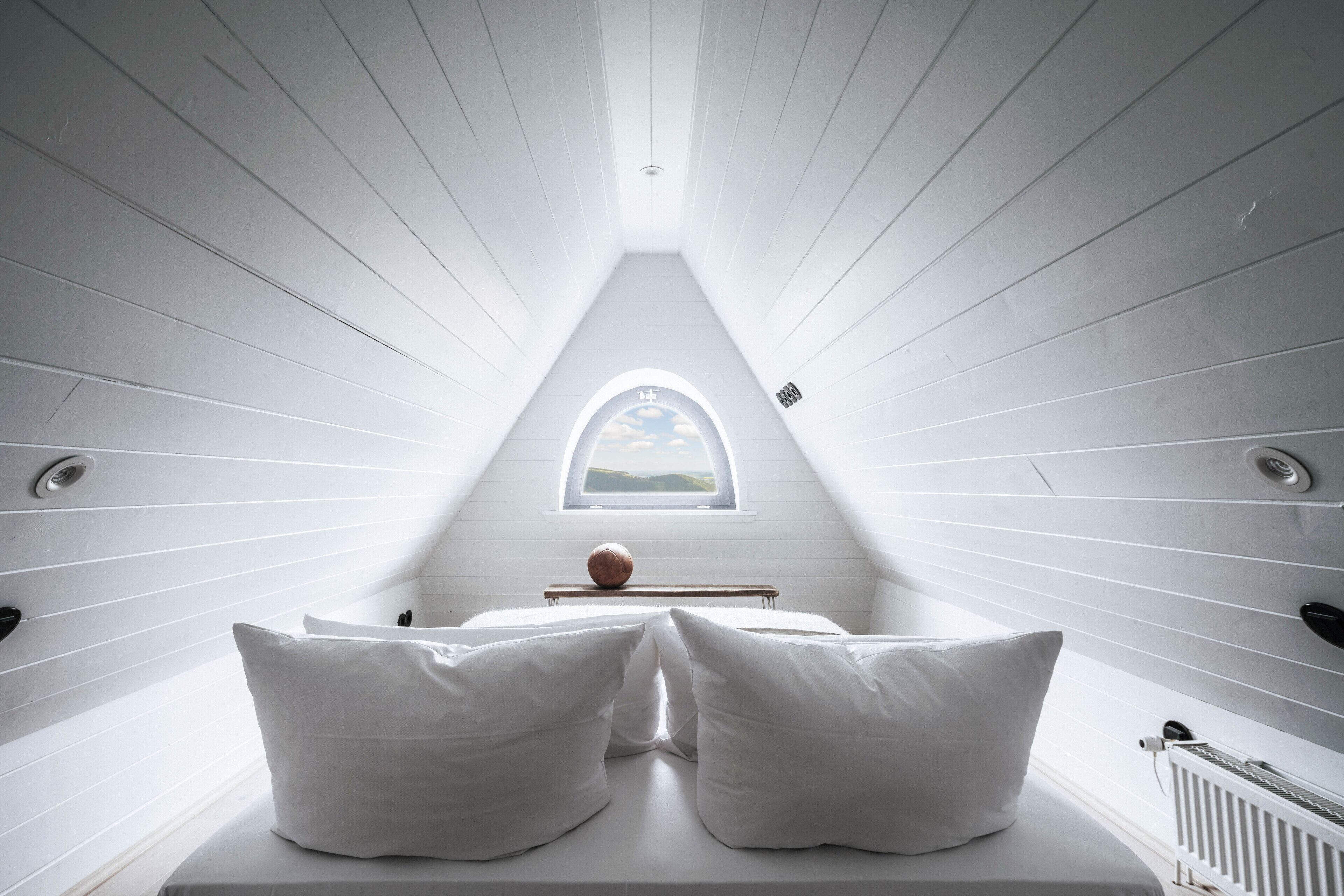 Ein schmales Zimmer mit hohen Decken, weißen Wänden und einem Oberlicht.