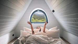 A bedroom with a sloped ceiling and a window with a view of a forest. - The Hearts Hotel Boutique und Event Resort (Braunlage)