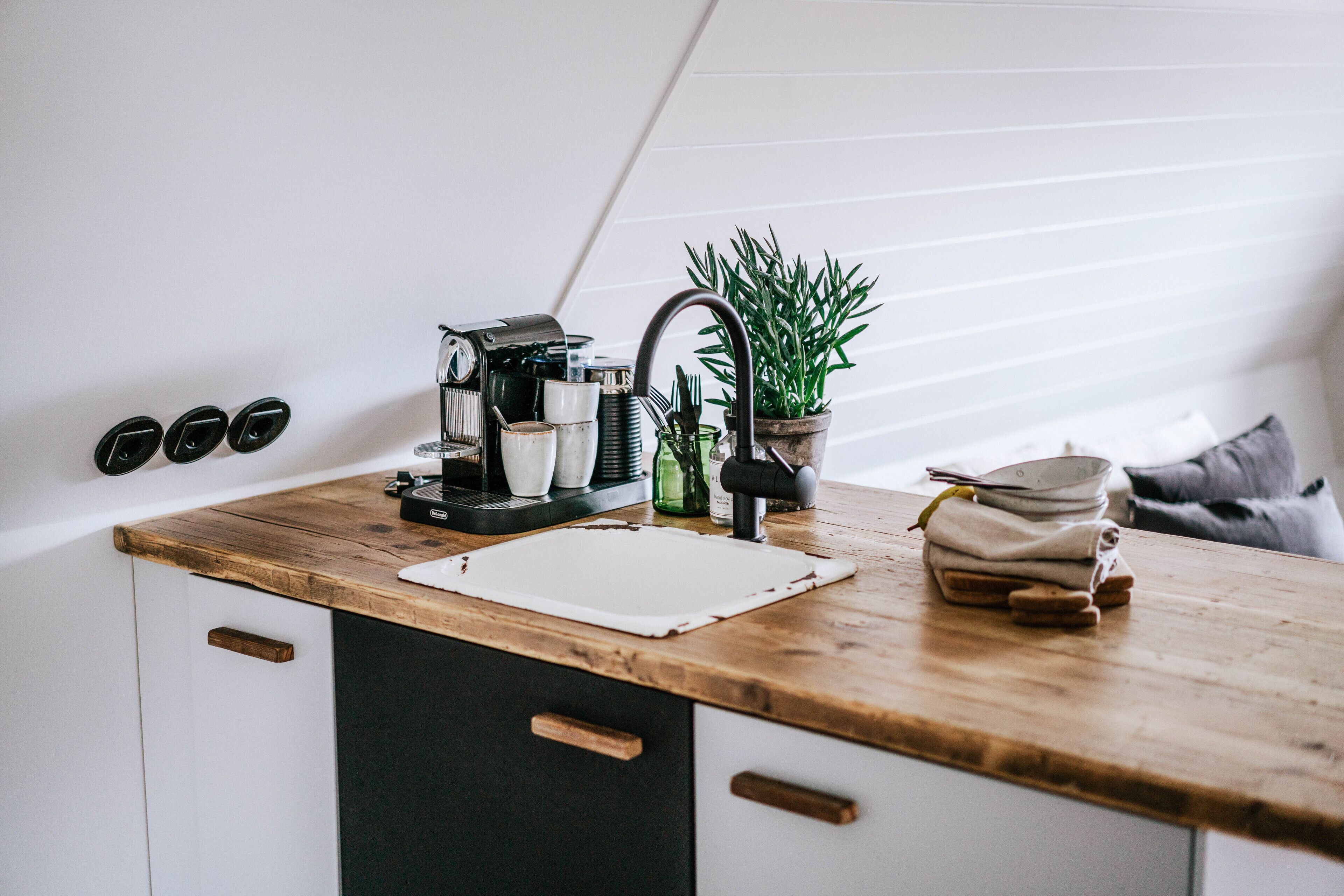 A kitchen with a wooden countertop, a sink, and various kitchen items.