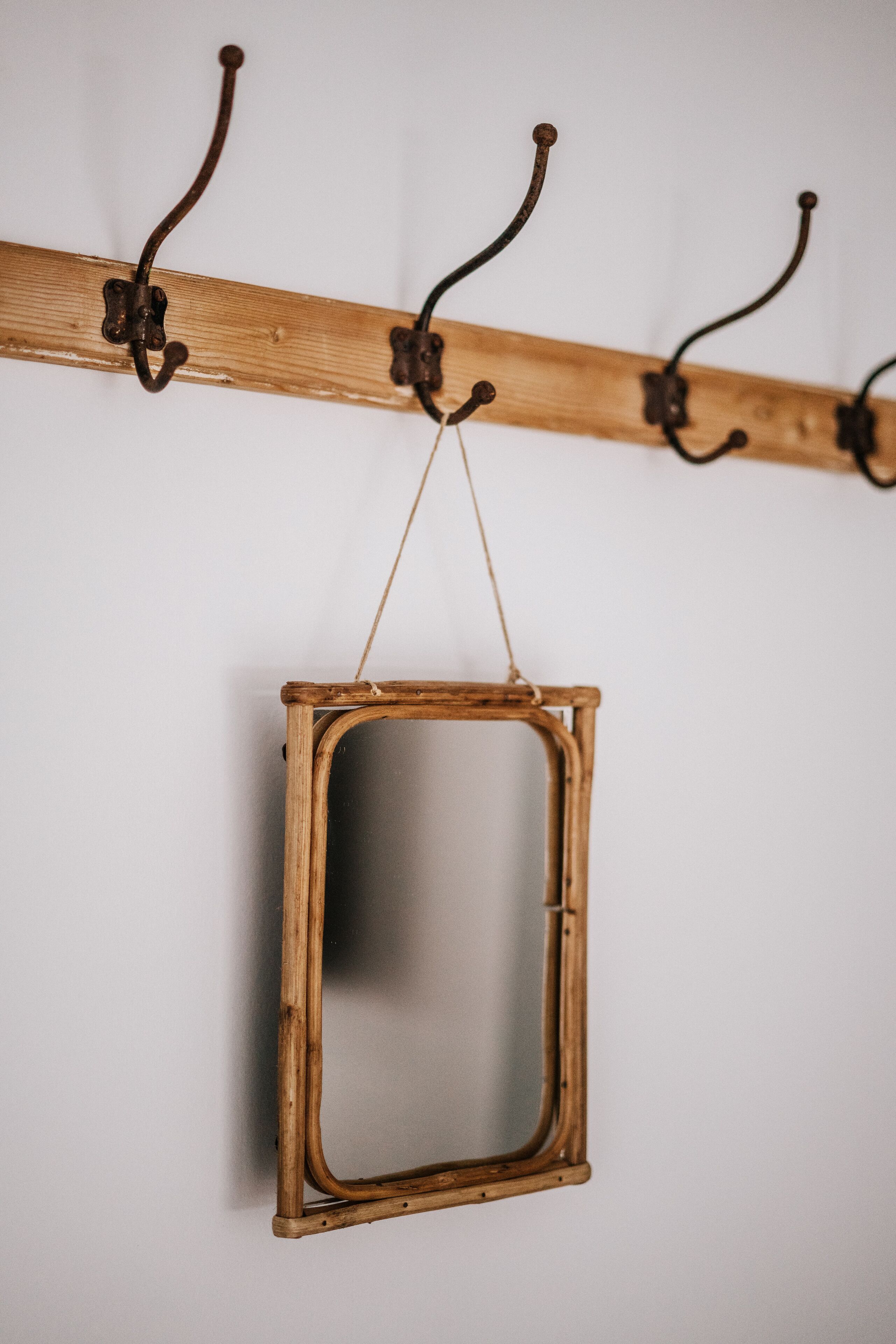 A wooden coat rack with hooks and a hanging mirror.